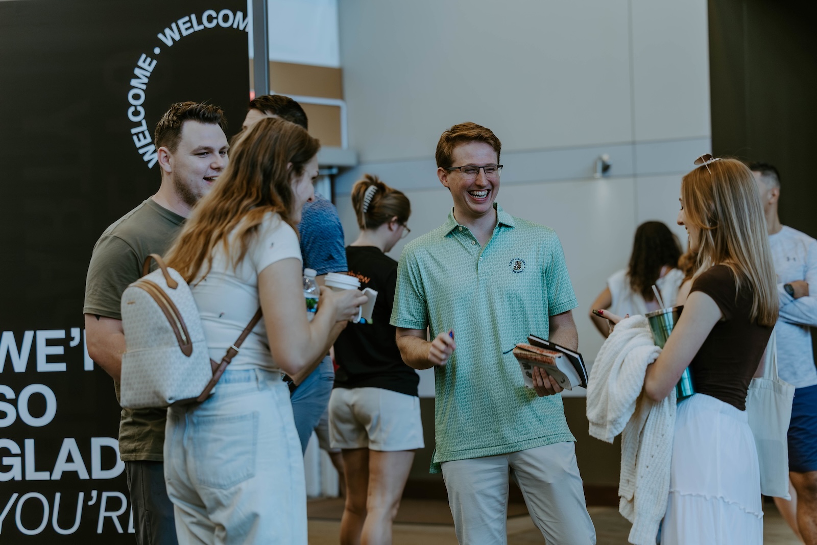 Several young adults chatting and laughing in a circle inside the church lobby