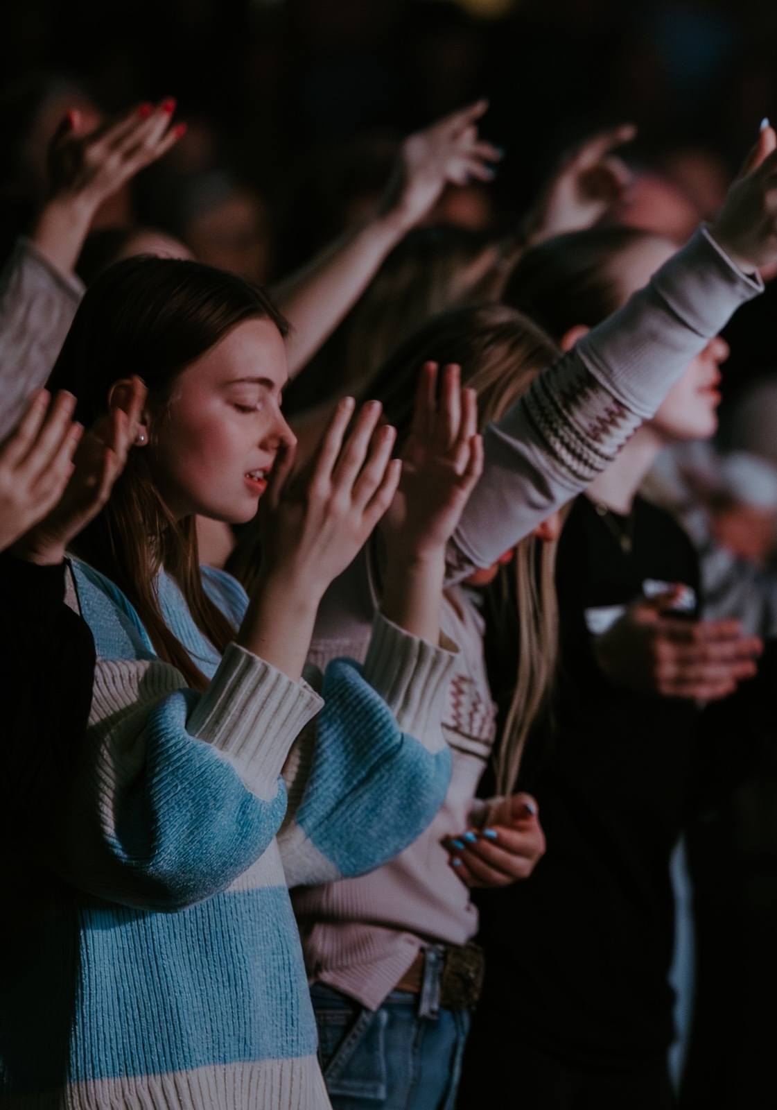 Young adults lifting their hands in a worship service